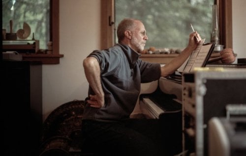 Composer John Luther Adams sits at a piano.